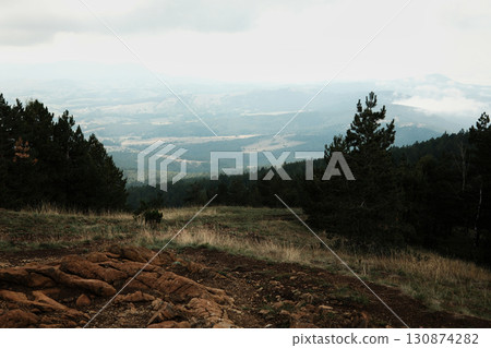 Rocky mountain slope with panoramic view of Divcibare, Serbia. Forested hills and misty valley seen from above 130874282