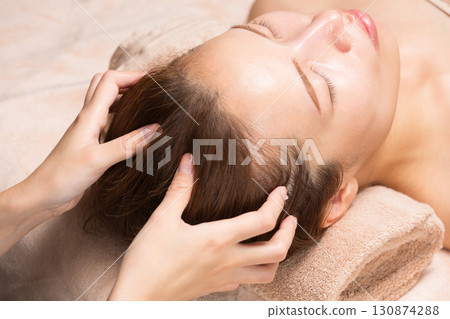 一位年輕的亞洲女性正在接受頭部按摩。 一位年輕的亞洲女性正在接受頭部按摩。 130874288