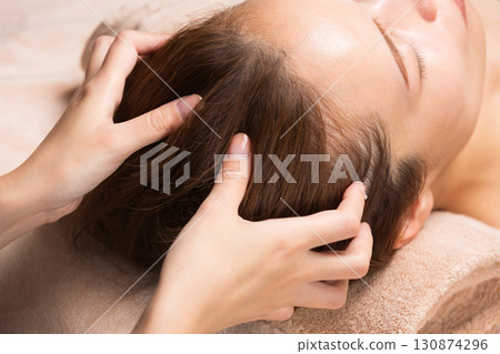 A young Asian woman is getting a head massage. A young Asian woman is getting a head massage. 130874296
