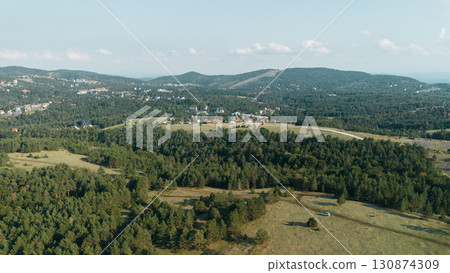 Aerial view of Divcibare village in Serbia, surrounded by dense green forests and mountain slopes 130874309