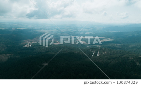 Aerial view over Divcibare, Serbia, showing vast forested hills, valleys, and dramatic clouds above the landscape 130874329