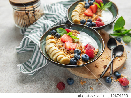 Healthy breakfast bowls with yogurt, granola, banana, and berries 130874393