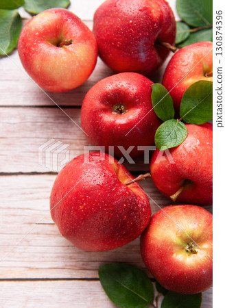 Fresh red apples resting on rustic wooden table 130874396