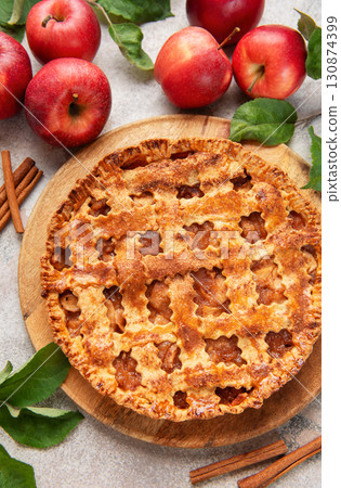 Freshly baked apple pie decorated with cinnamon sticks and apple leaves 130874399