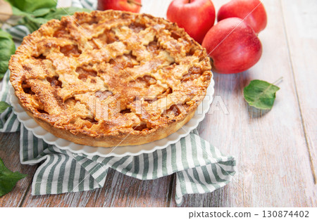 Freshly baked apple pie with red apples and leaves on rustic wooden table 130874402