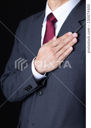 Middle-aged male businessman in a suit holding his hand on his chest Middle-aged male businessman in a suit holding his hand on his chest 130874800