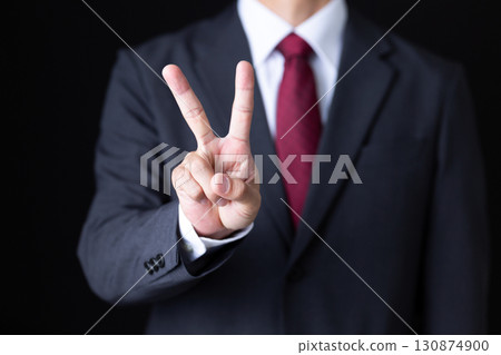 A middle-aged male businessman in a suit holding up two fingers A middle-aged male businessman in a suit holding up two fingers 130874900