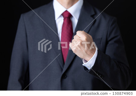 Middle-aged male businessman in a suit making a fist pump 130874903
