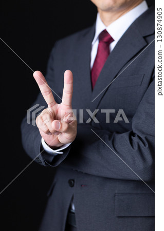 A middle-aged male businessman in a suit holding up two fingers A middle-aged male businessman in a suit holding up two fingers 130874905