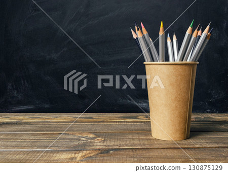 Wooden table with a brown cup of pencils on it Wooden table with a brown cup of pencils on it 130875129