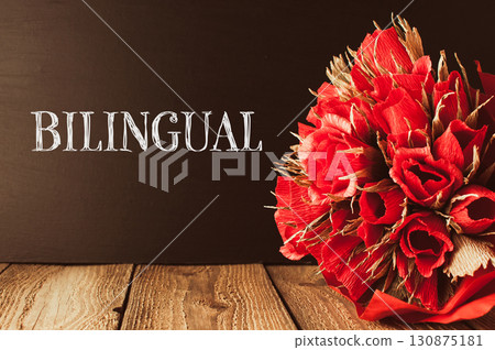 Bouquet of red roses is on a wooden table with the word bilingual 130875181