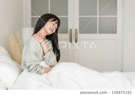 一位年輕女子因床上用品和枕頭不合適而出現肩膀僵硬的症狀（頸部僵硬、疼痛、睡眠品質、床上用品、不合適） 130875191