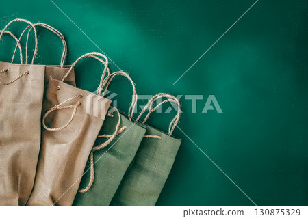 Row of colorful shopping bags are displayed on a green background. Row of colorful shopping bags are displayed on a green background. 130875329