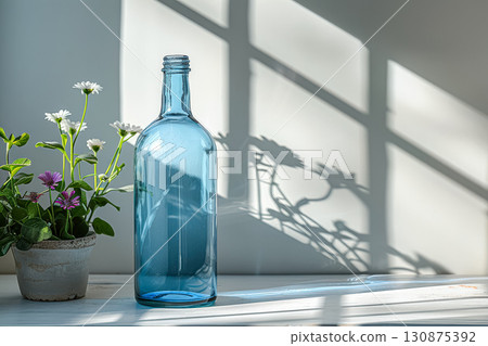 Blue bottle sits on a windowsill next to a plant. 130875392