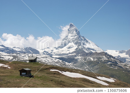 A majestic panoramic view of the Matterhorn in midsummer from a trekking course through the grasslands 130875606