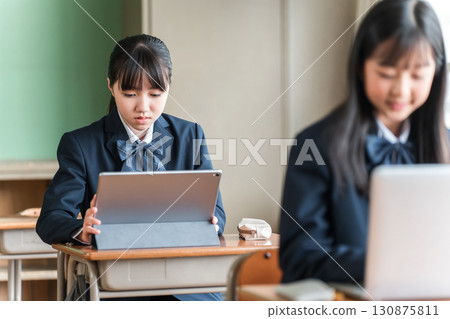 Junior high and high school girls in uniforms studying using computers and tablets Junior high and high school girls in uniforms studying using computers and tablets 130875811