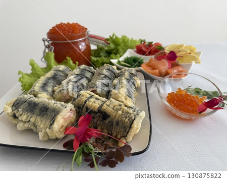 fried rolls in batter decorated sushi on a plate. Sushi is the traditional Asian and Japanese food. Roll of sushi prepared from raw fish and a special rice. Diet healthy food. 130875822