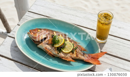 Grilled red snapper with lemon served with passion fruit juice on a white table at the beach Grilled red snapper with lemon served with passion fruit juice on a white table at the beach 130876030