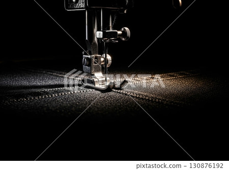 Vintage sewing machine with a presser foot stitching a seam on dark denim fabric at a tailor shop Vintage sewing machine with a presser foot stitching a seam on dark denim fabric at a tailor shop 130876192