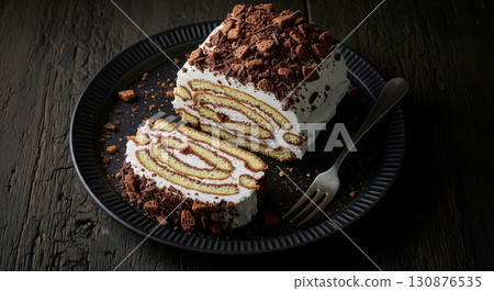 Chocolate ripple cake with a creamy topping and biscuit crumbs served on a rustic dark table 130876535