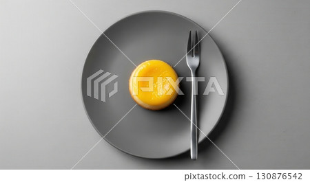 Top view of a Brazilian quindim dessert on a grey plate in a minimalist style with a fork 130876542