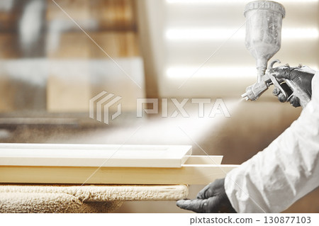 Close-up image of man spraying with gun to the wood. 130877103