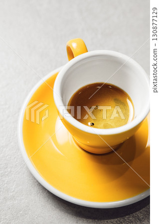 Close-up View of Rich Espresso Shot in Yellow Cup on Light Gray Table 130877129