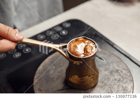 Traditional Turkish Coffee Preparation in a Dzezva on Stovetop With Pouring Spoon Traditional Turkish Coffee Preparation in a Dzezva on Stovetop With Pouring Spoon 130877136