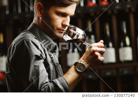 Bokal of red wine on background, male sommelier appreciating drink 130877140