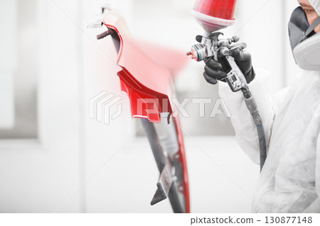 Close-up, hand of repairman painting car body elements in the paint chamber. 130877148