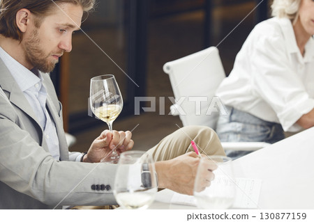 sommelier tasting white wine and making notes to degustation card during wine expert training. sommelier tasting white wine and making notes to degustation card during wine expert training. 130877159