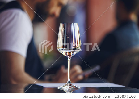 White wine glass at the table on summer terrace of restaurant background. Blind tasting concept.  130877166