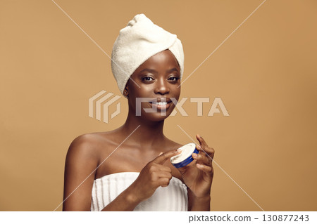 Beauty portrait of black woman holding blue cosmetic tin. 130877243