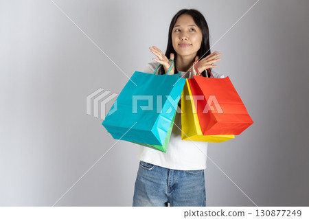 Young girl is holding three colorful shopping bags and appears to be happy or Young girl is holding three colorful shopping bags and appears to be happy or 130877249