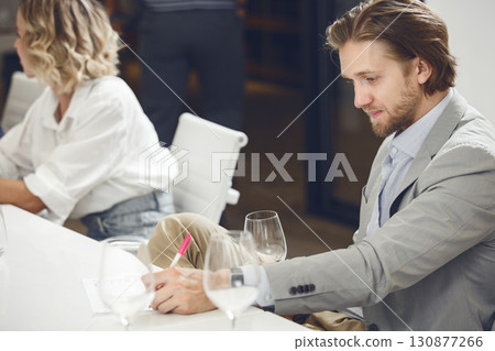 Successful looking male sommelier smelling and tasting white wine into glass during sommelier training. Successful looking male sommelier smelling and tasting white wine into glass during sommelier training. 130877266