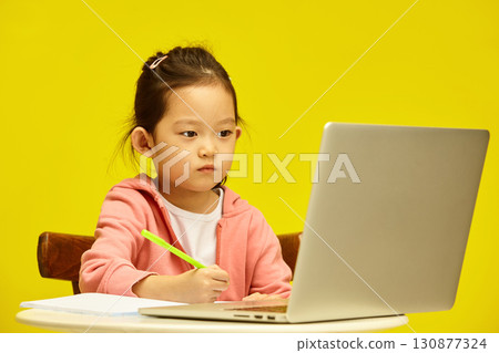 Studious Asian first grader Girl Concentrates on Distance Learning Homework. Little Korean school girl Deep in Study with Online Resources Studious Asian first grader Girl Concentrates on Distance Learning Homework. Little Korean school girl Deep in Study with Online Resources 130877324