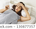 Unhealthy woman with high temperature measures with thermometer, feels bad, sick ill suffers  130877357