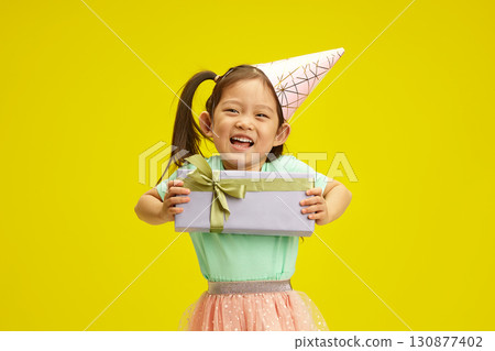 Happy Little Child Girl with Birthday Gift Box on Sunny Yellow Background, Isolated Portrait Happy Little Child Girl with Birthday Gift Box on Sunny Yellow Background, Isolated Portrait 130877402