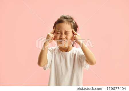 Five year old Japanese appearance Girl Concentrating with Eyes Closed and Fingers on Temples stands over pink isolated Five year old Japanese appearance Girl Concentrating with Eyes Closed and Fingers on Temples stands over pink isolated 130877404