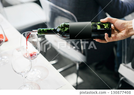 Elegant Red Wine Pouring into Glass on Event Close-up Elegant Red Wine Pouring into Glass on Event Close-up 130877408