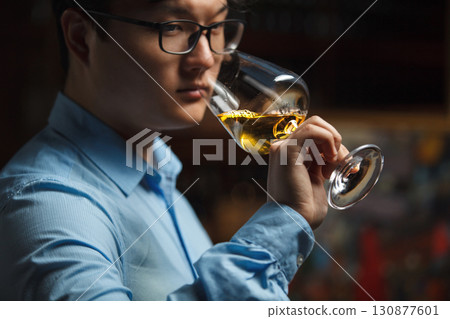Asian Sommelier Expertly Assessing White Wine Characteristics Through Aroma Asian Sommelier Expertly Assessing White Wine Characteristics Through Aroma 130877601