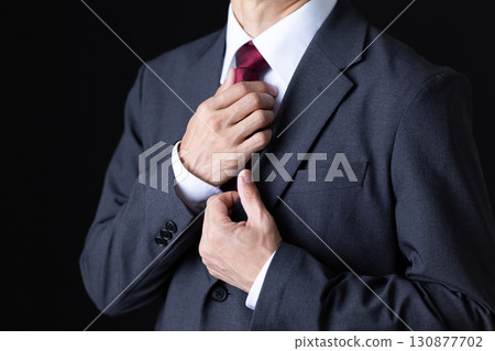 一位身穿西裝的中年男性商人正在打扮自己 一位身穿西裝的中年男性商人正在打扮自己 130877702