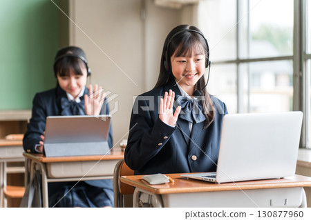 Elementary school, junior high school, and high school girls waving at their computers during class 130877960