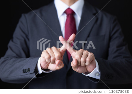 A middle-aged male businessman in a suit making a cross sign gesture A middle-aged male businessman in a suit making a cross sign gesture 130878088