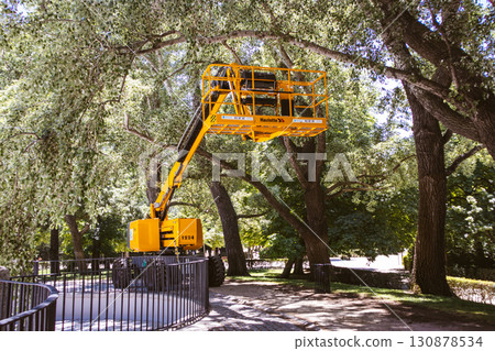 Madrid, Spain 1 May 2024 Aerial lift platform used for tree maintenance in a sunny park setting, nature and industry. 130878534