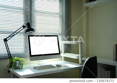 Modern home office workspace with desktop computer, and desk lamp by the window Modern home office workspace with desktop computer, and desk lamp by the window 130879172