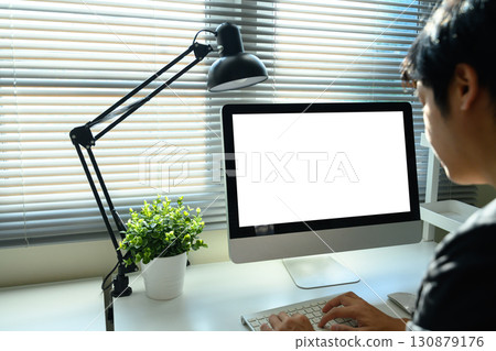 Businessman working in modern home office with blank white screen and natural daylight Businessman working in modern home office with blank white screen and natural daylight 130879176