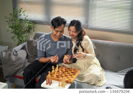 Smiling man and woman enjoying quality time and strategy board game at home 130879206