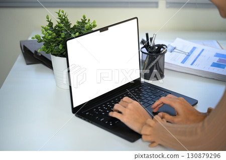 Close up of hands typing on laptop with blank screen at modern office desk 130879296