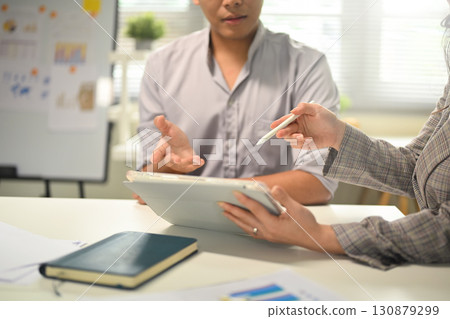 Business colleagues discussing ideas while using a digital tablet during office meeting 130879299